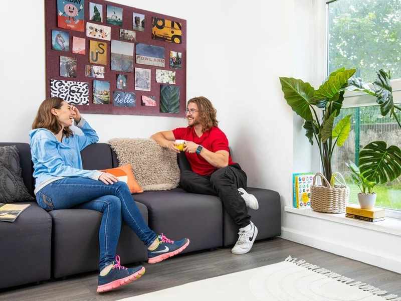 Two young adults sitting and talking on a dark grey sofa
