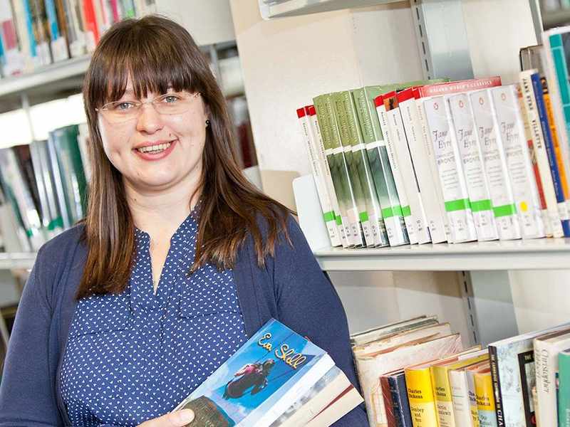 A person stands in front of bookshelves in a library.