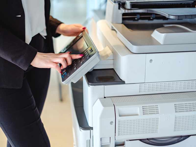 A woman presses the button on a large printer