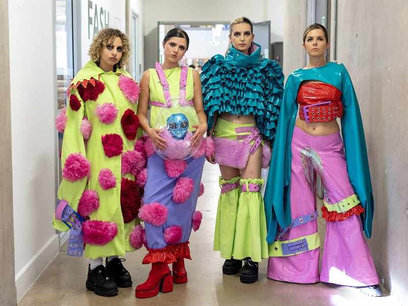 A group of four fashion models pose in a corridor.