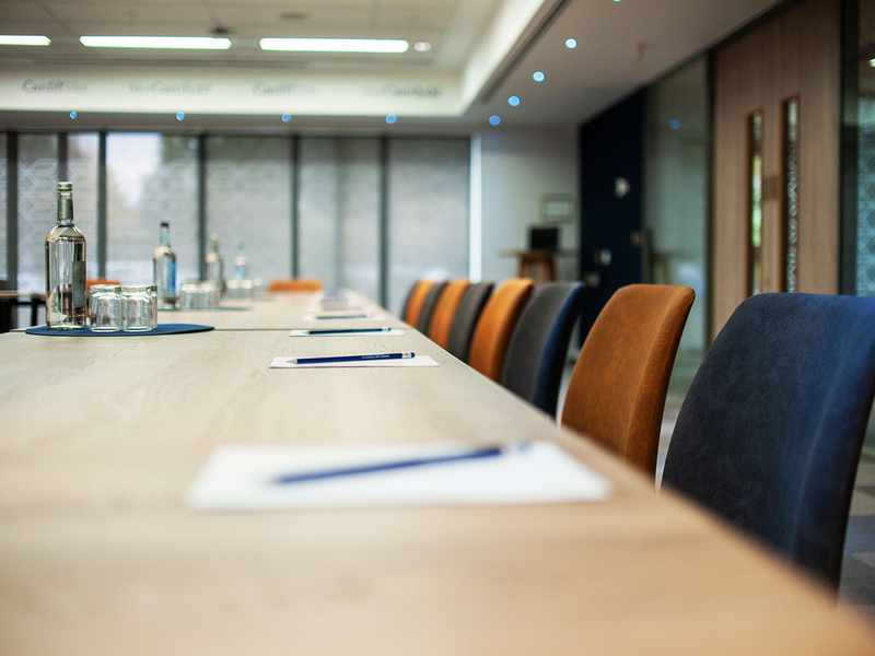 A conference table surrounded by chairs, featuring a bottle of water at the center, ready for a meeting.