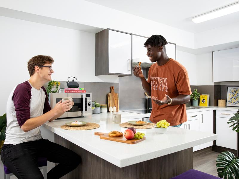 Two young men talk while eating at a kitchen counter island