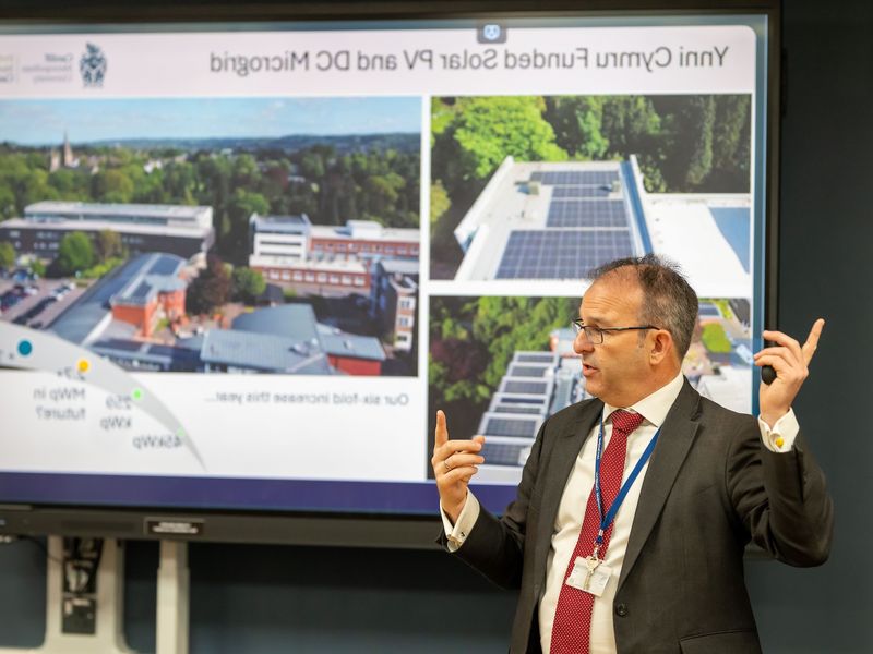 A member of Cardiff Met staff presents a presentation in front of a digital whiteboard