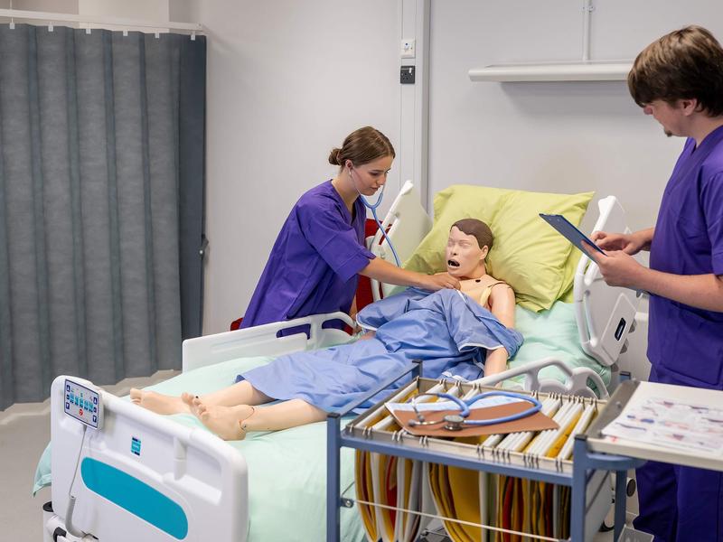 Nursing student places stethoscope on manikin