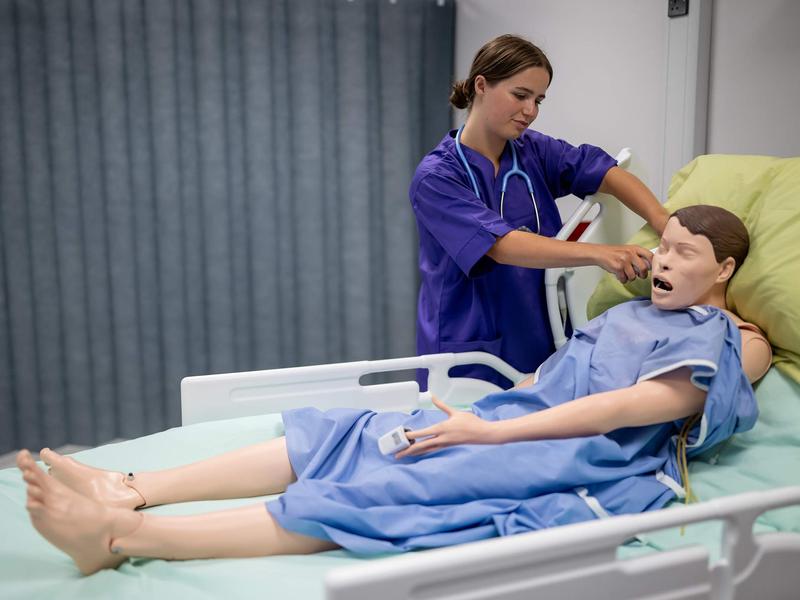 Nursing student uses thermometer on manikin