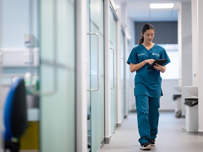 Student holding tablet while walking through Allied Clinical Health Hub