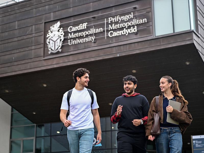 Three students walking and talking outside of the Cardiff School of Management