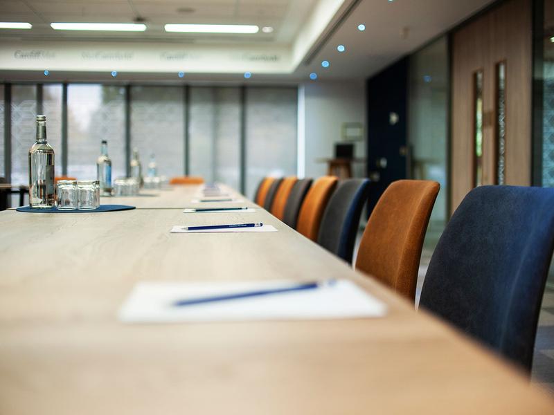 A conference table surrounded by chairs, featuring a bottle of water at the center, ready for a meeting.