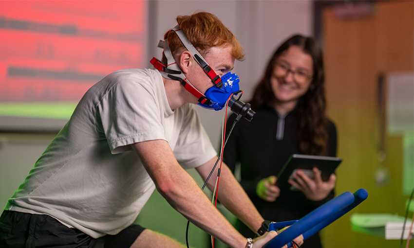 A person on an exercise bike wearing an oxygen mask.