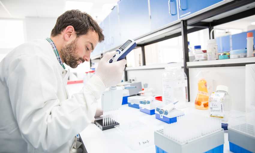 A young man in white laboratory coat conducts research