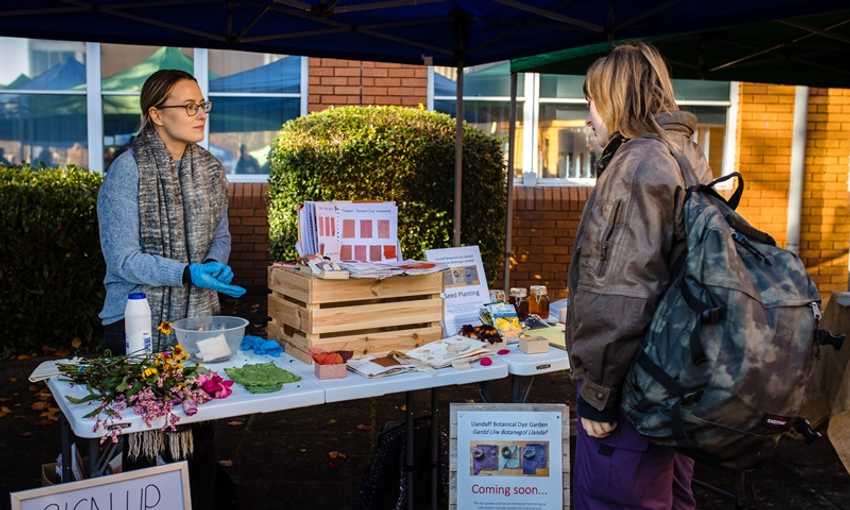 A young woman stands at a Sustainability information stand during a Community Event on Llandaff Campus