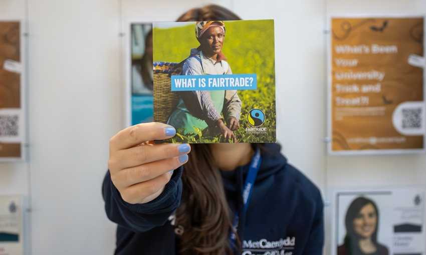 Cardiff Met staff member holds a Fairtrade information leaflet in front of their face