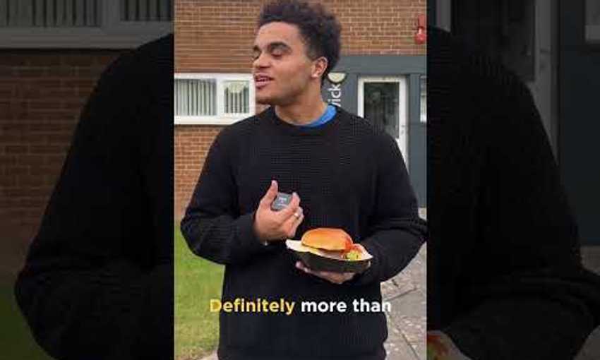 Student holding a burger speaking to video operator