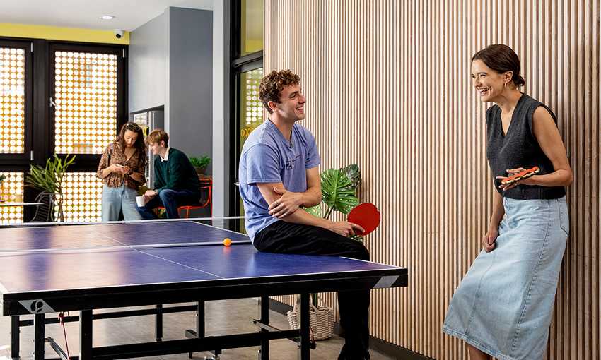 Two individuals playing ping pong in a communal area, showcasing a fun break from studying in a collaborative environment.