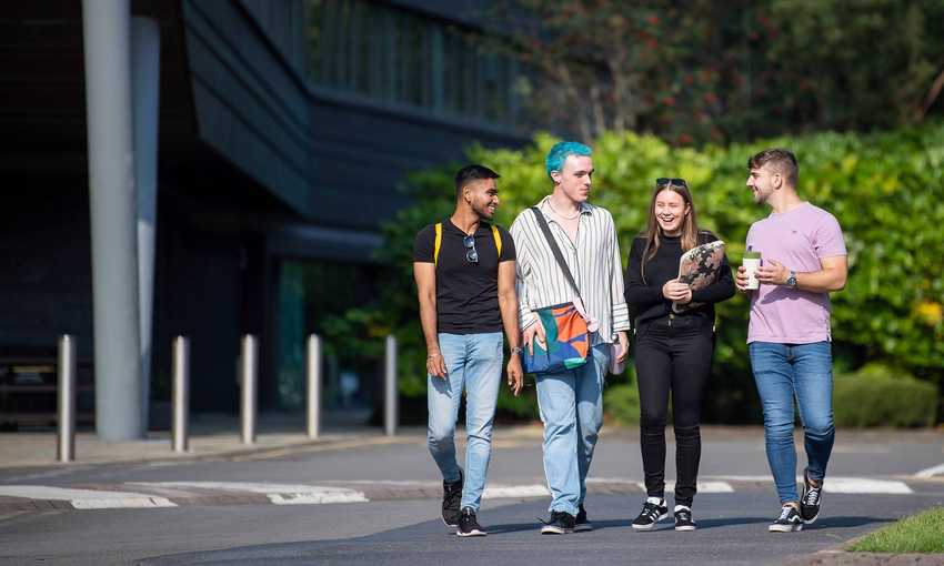 Group of 4 students walking through campus