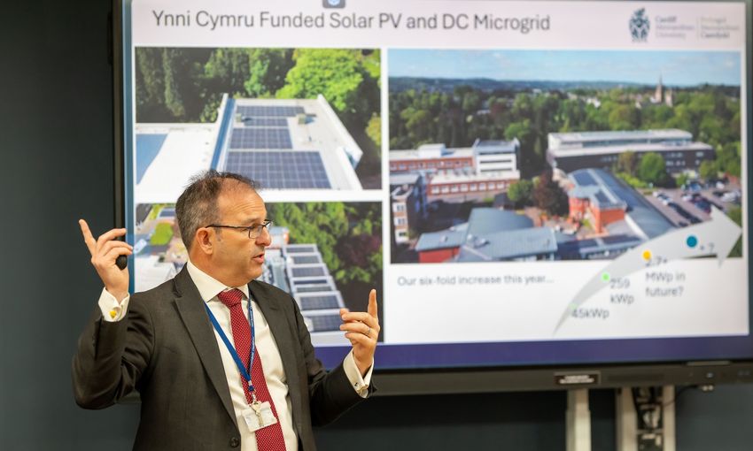 A member of Cardiff Met staff presents a presentation in front of a digital whiteboard