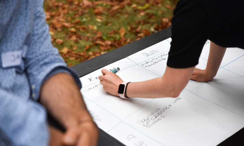 A close-up of a person writing on a large sheet of paper with a marker pen.