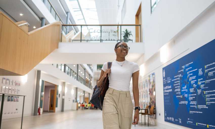 A student walks through the bottom floor of the Cardiff School of Management
