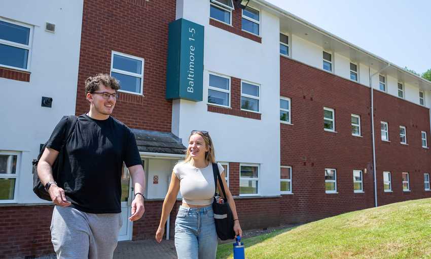 Two people walking together outside an accommodation block at Cardiff Met.