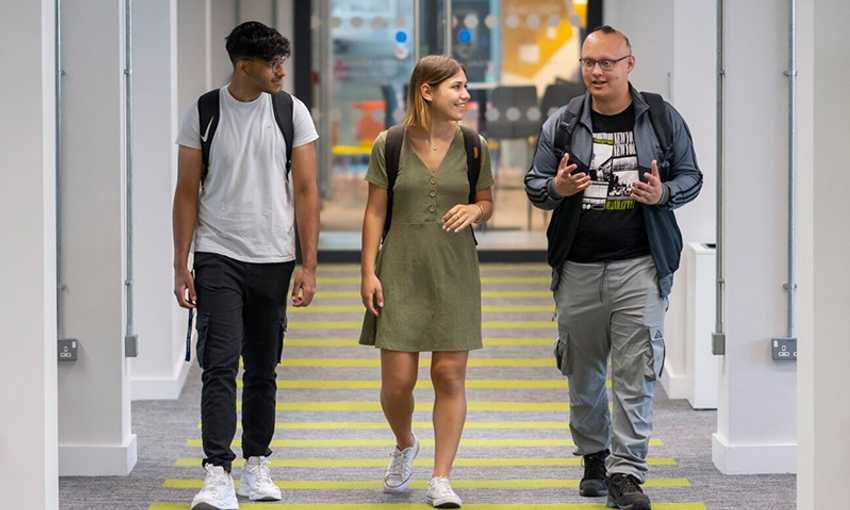 Three students walking together down a corridor on the University campus