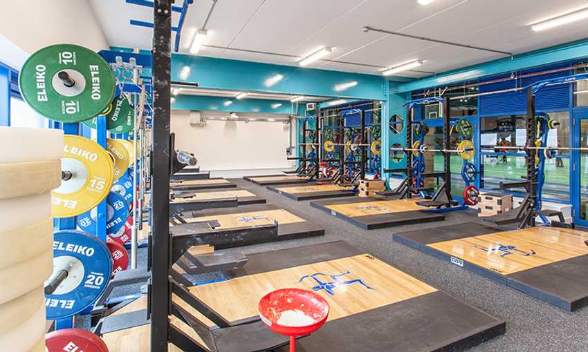 A training space with multiple lifting platforms, squat racks, and colorful weight plates.