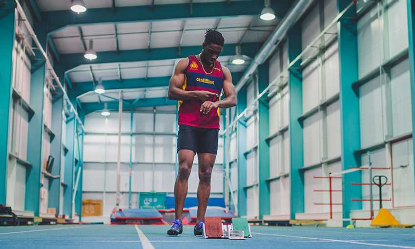 A man is positioned on a race track inside an indoor arena, showcasing a dynamic and energetic environment.