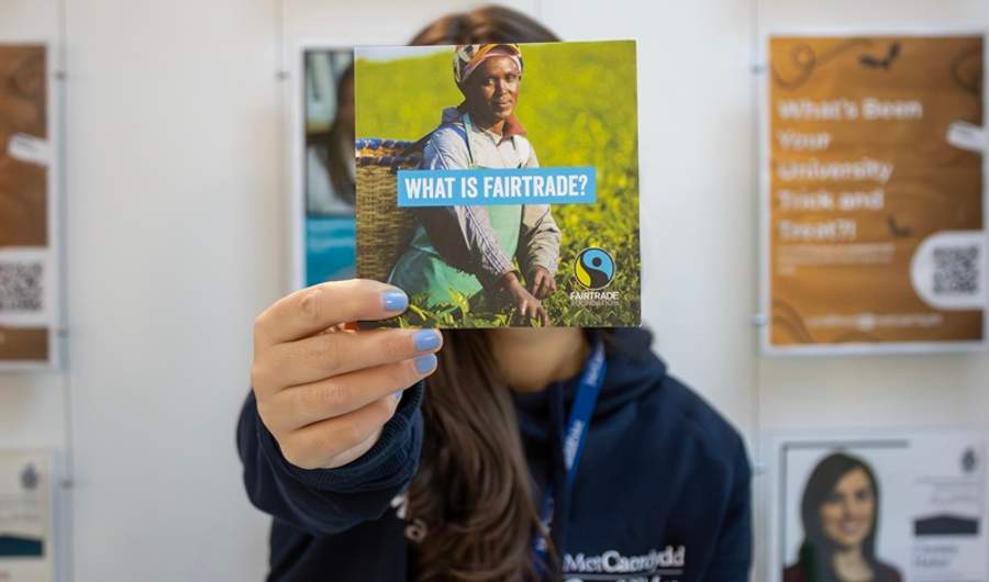 Cardiff Met staff member holds a Fairtrade information leaflet in front of their face