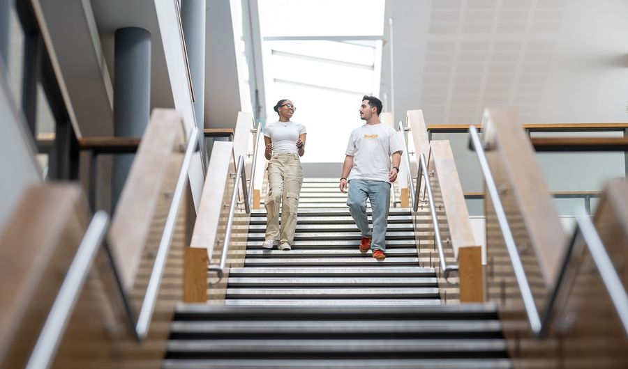 Two students walk down the stairs of the Cardiff School of Management