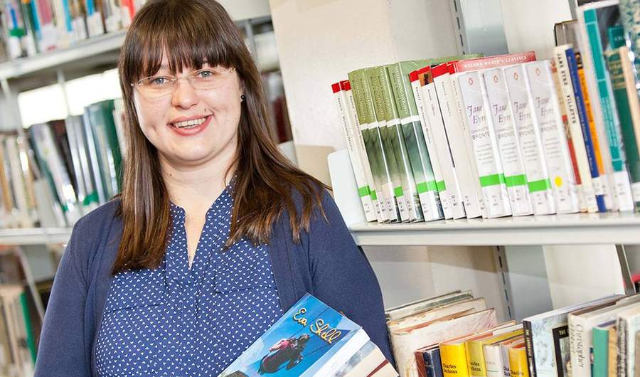 A person stands in front of bookshelves in a library.