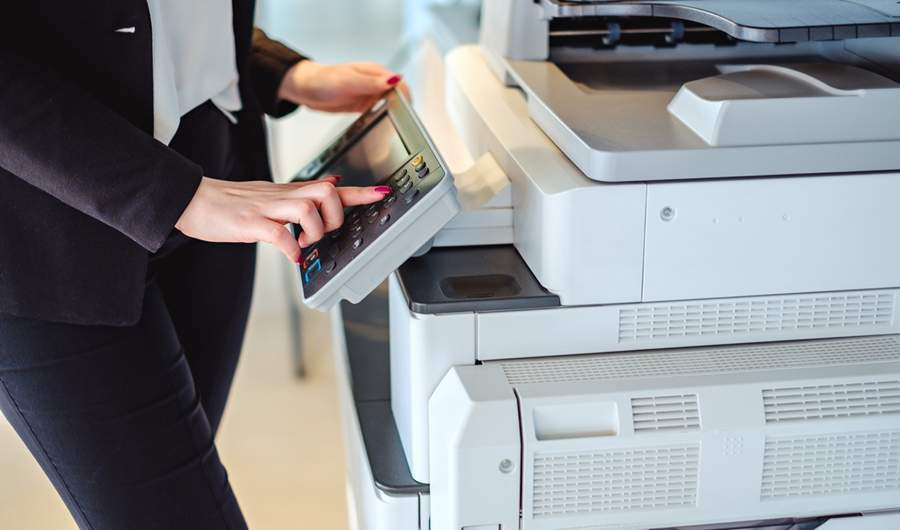 A woman presses the button on a large printer