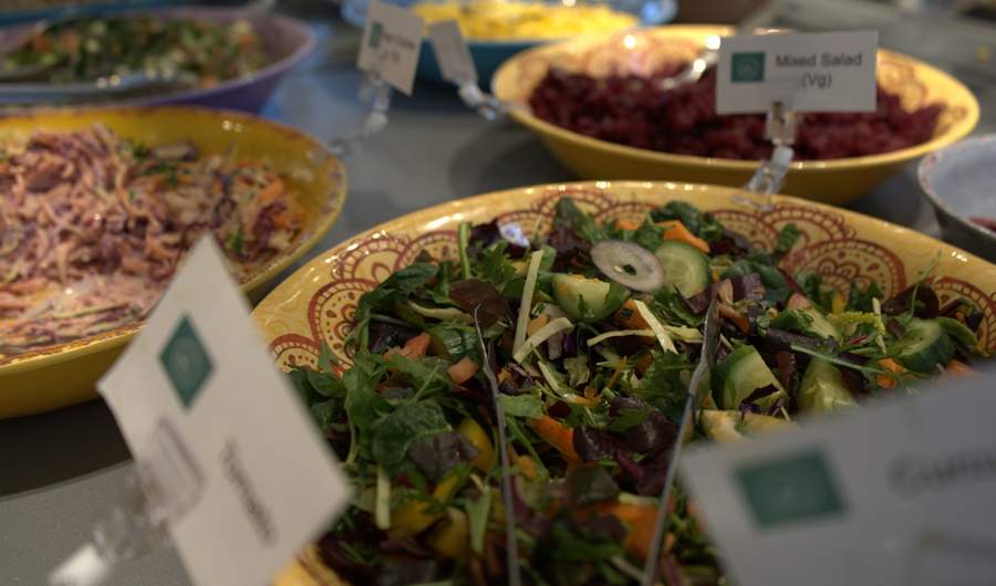 A selection of salads on display in bowls, with accompanying information signs