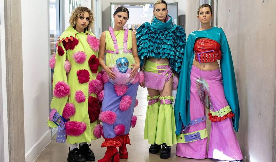 A group of four fashion models pose in a corridor.