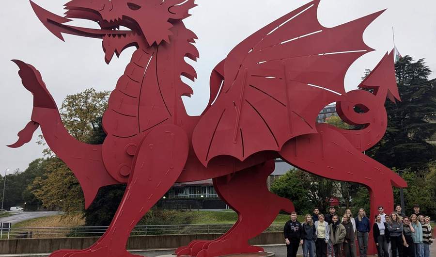 A group of people stand in front of a giant metal red dragon.