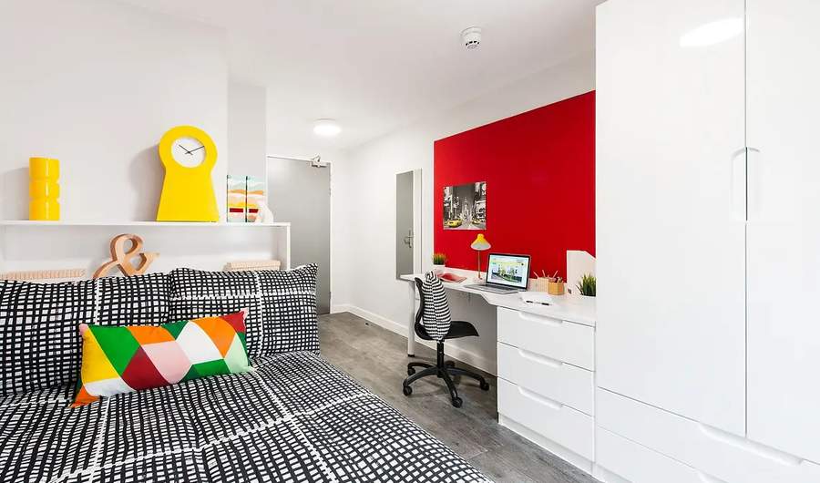 A bright, student accommodation room with bed, desk and wardrobe