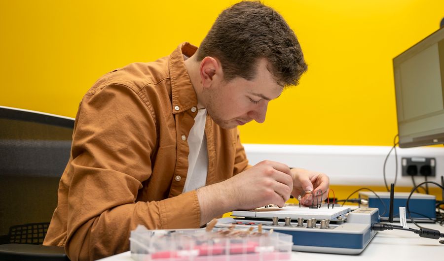 CST student works on a small circuit board at their desk