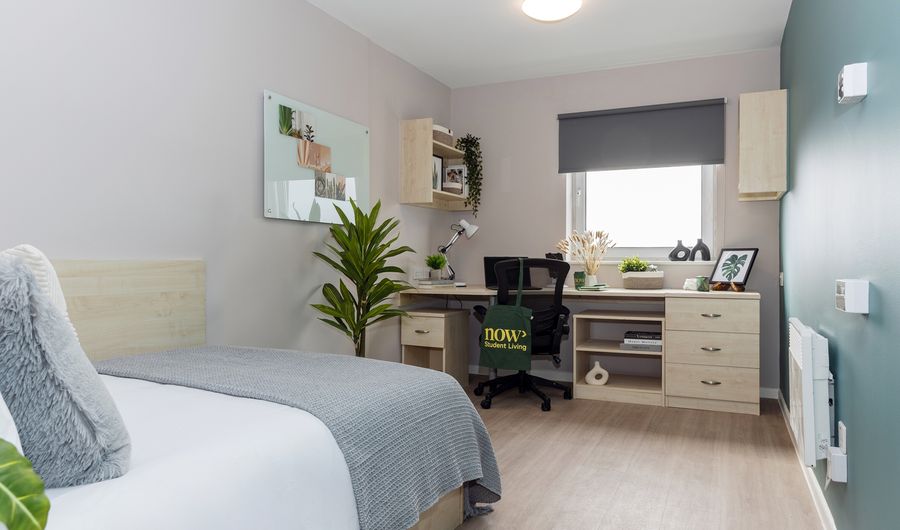 A student bedroom with bed and large study desk