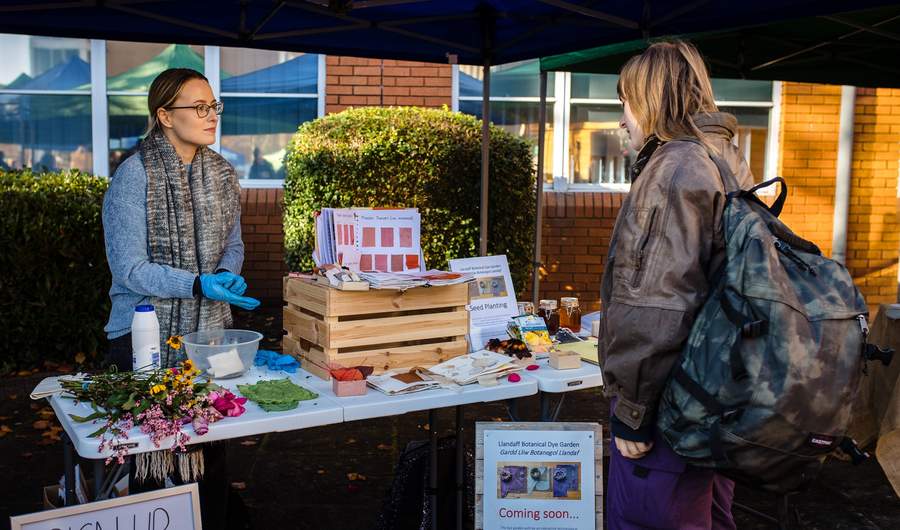 A young woman stands at a Sustainability information stand during a Community Event on Llandaff Campus