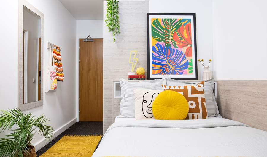 A colourful bedroom with bright bedding and striking artwork on the walls