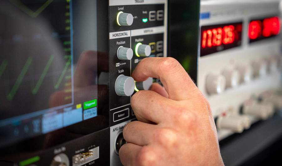 Close-up of hand turning dial on an oscilloscope
