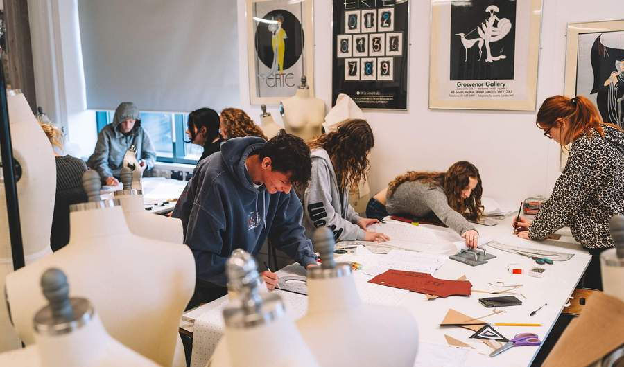 A group of students working with fabric patterns. There are several mannequins in the foreground.