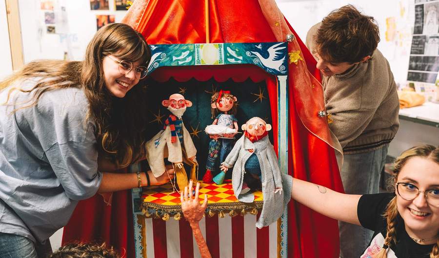 A group of students holding small hand puppets.