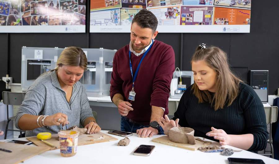 Lecturer with student teachers working with clay