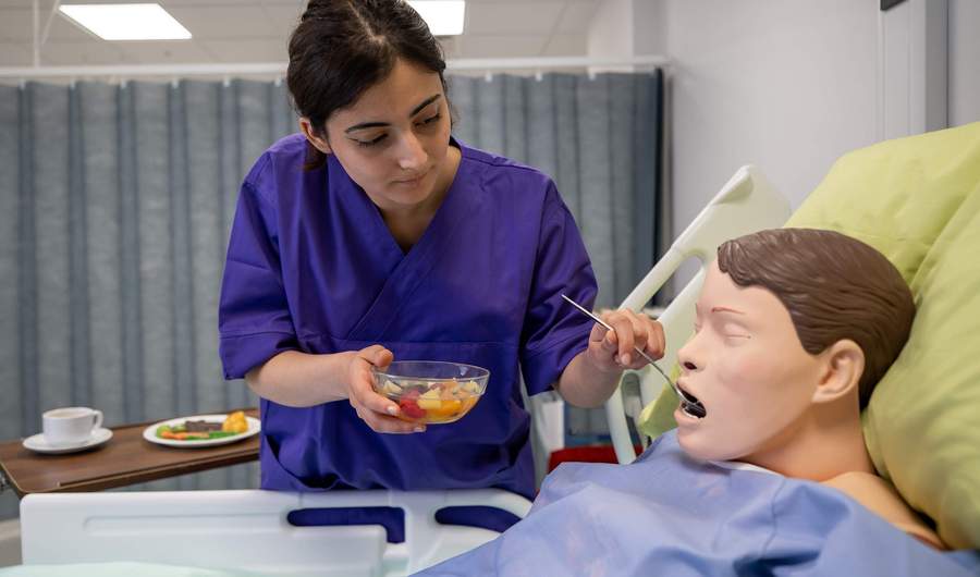 Nursing student feeding manikin