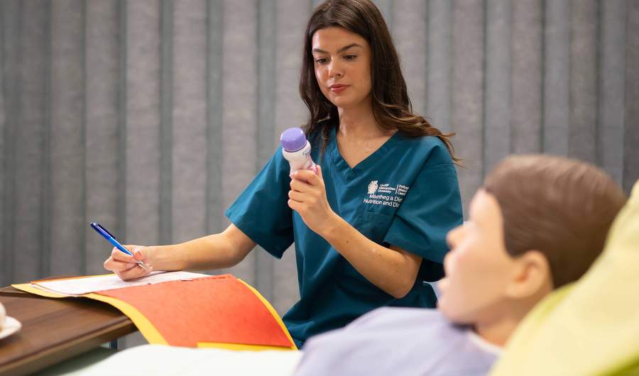 Nutrition and Dietetics student with manikin in Allied Clinical Health Hub Simulation Suite