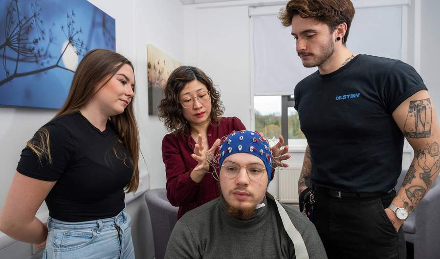 A seated person wearing an EEG cap, as three other people look on.