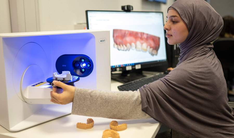 Student placing dental cast into 3d scanner