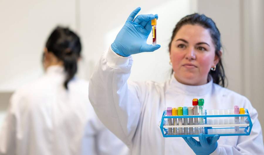 Student in laboratory coat holding test tube
