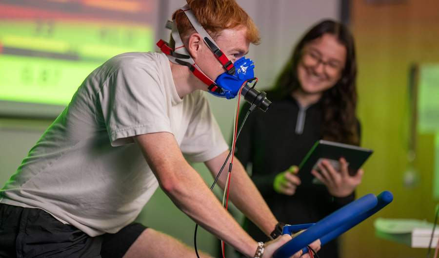 Student wearing oxygen mask on exercise bike