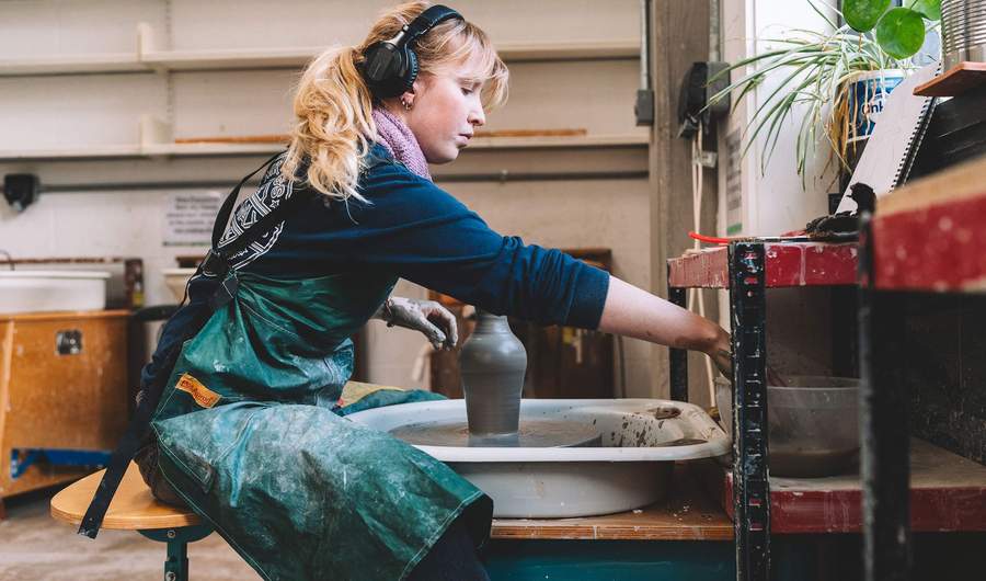 A student makes a vase using a pottery wheel.