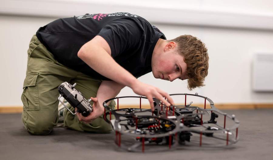 A student works with a small drone quadcopter.